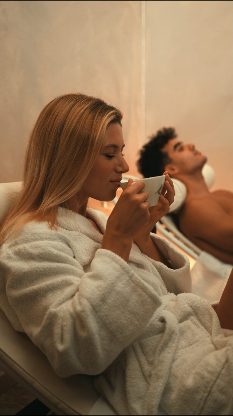 Un'ospite in accappatoio beve una tisana nella zona relax